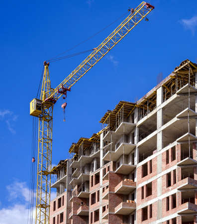 modern apartment building with tower crane on blue sky background