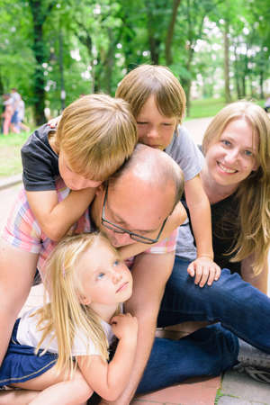 family with boys and girl relax outdoors in public park