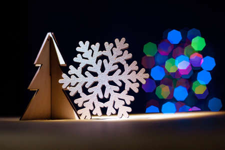 Christmas toy tree with wooden snowflake on colorful bokeh blur light background