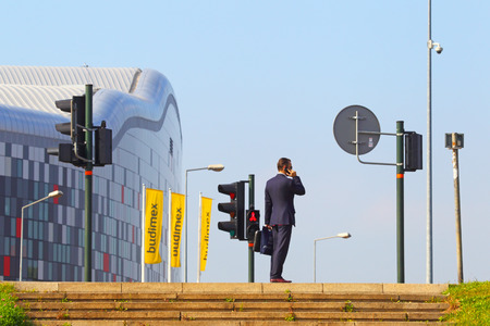 KRAKOW, POLAND-18 September, 2014:The business man speaks by phone at the crosswalk in Krakow, Poland on September 18, 2014.のeditorial素材