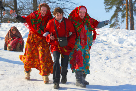 Gatchina,Leningrad region,Russia-17 March, 2013:Two young girls and the guy in national suits ride an ice slope in Gatchina, Leningrad region, Russia March 17,2013.A  Russian holiday - Maslenitsaのeditorial素材