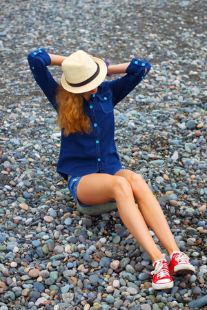 Young blonde girl in a hat on the beach.A seaside holiday in a vacation.The photo is tinted in a retro style.の写真素材