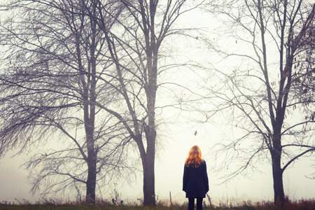 Blonde woman on walk.Autumn wood. Fog background. Quiet landscape.The photo is tinted.の写真素材