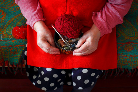 Hands of an elderly woman. Knitting threads.The photo is tinted in a retro style.