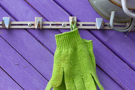 Green gloves against violet boards. A hanger on a wall of the private house. abstract symbolの写真素材