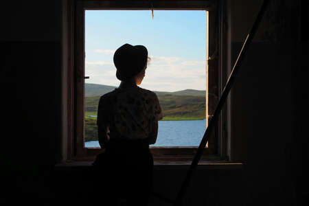 The young lady looks out of the window. Depression.Photo tinted and styled with vintage...