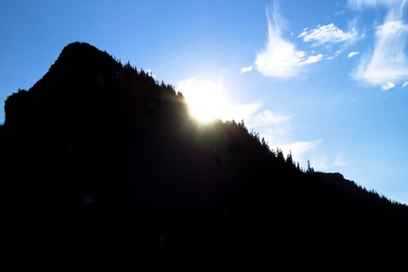 Blue sky and sunset behind the dark mountainの写真素材