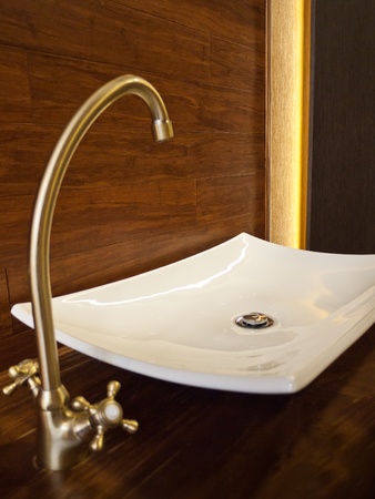 White sink with golden basin mixer and wooden backgroundの写真素材