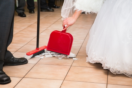 Bride and groom sweep up the pieces of happinessの写真素材