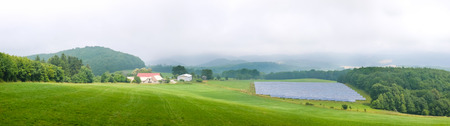 Photovoltaic system installation on green field surrounded by forests