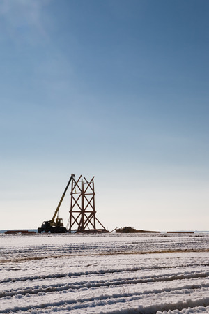 Crane building a wooden structure outside in snowy landscape under clear blue skyの写真素材