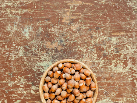 Hazelnuts in a bowl on rustic table with copy space for text. Organic food concept