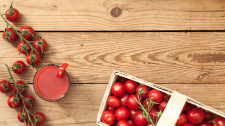 Wooden basket on the table full of fresh picked tomatoes. Fresh and healthy summer vegetable for eating and drinkingの写真素材