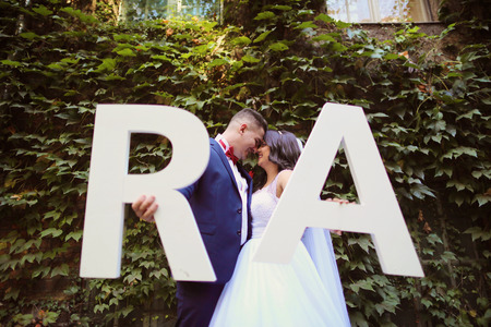 Bride and groom holding R and A big white lettersの写真素材
