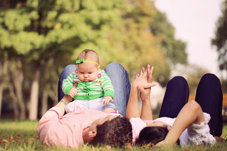 Parents lie down holding her baby girl up