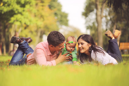 Parents with baby girl sitting on grass in the parkの写真素材