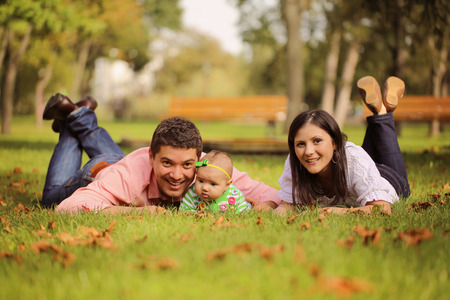 Parents with baby girl sitting on grass in the parkの写真素材