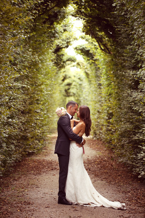 Vertical photograph of a bride and groom embracing surrounded by treesの写真素材