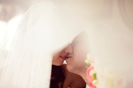 Bride and groom kissing behind the veilの写真素材