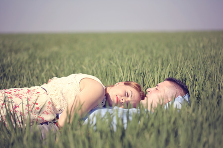 Beautiful cheerful couple lying on green grassの写真素材