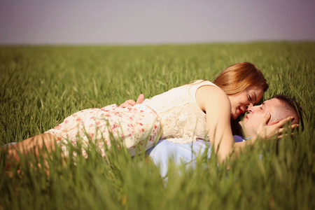 Beautiful cheerful couple lying on green grassの写真素材
