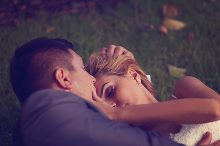 Bride and groom sitting on grassの写真素材