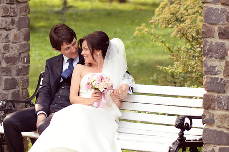 Bride and groom sitting on benchの写真素材