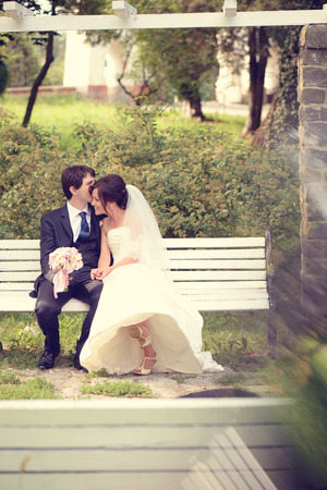Bride and groom sitting on benchの写真素材