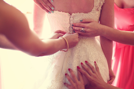 Hands helping the bride with the wedding dressの写真素材