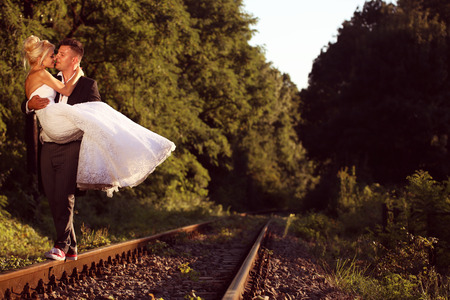 Groom carrying his bride on a railroadの写真素材