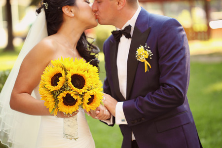Hands of a bride and groom holding sunflower bouquetの写真素材