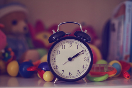 Clock surrounded by colorful toysの写真素材