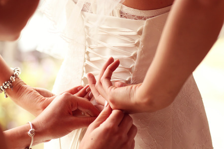 Hands helping the bride with wedding dressの写真素材