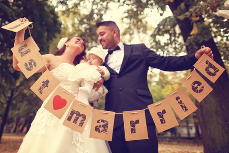Bride, groom and baby girl in the parkの写真素材