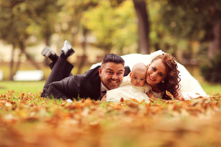Bride and groom laying on autumn leavesの写真素材