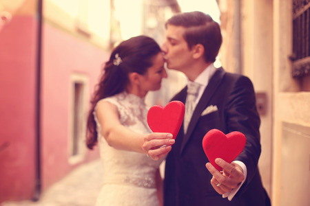 Bride and groom holding red heartsの写真素材