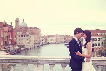 Bride and groom kissing on a bridgeの写真素材