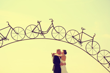 Bride and groom under a iron arch in a bicycle formの写真素材