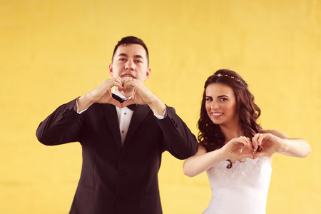 Bride and groom making love sign
