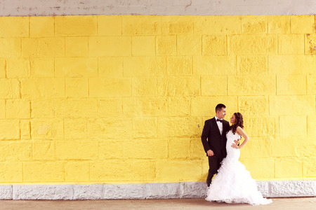 Bride and groom against yellow wallの写真素材