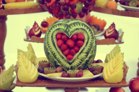 Carved watermelon on table with many other fruitsの写真素材