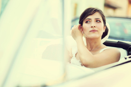 Beautiful happy young bride looking from red retro auto carの写真素材
