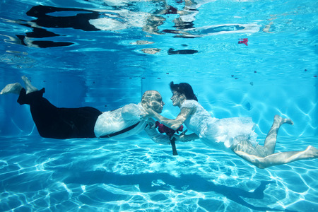 Bride and groom kissing underwater wedding diving red flowersの写真素材