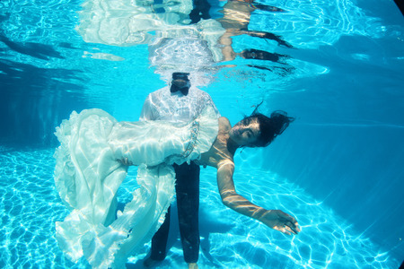 Bride and groom kissing underwater holdingの写真素材