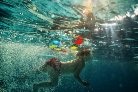 The little girl in the water park swimming underwater and smilingの写真素材