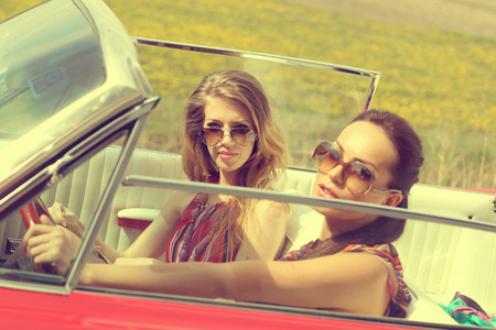 Beautiful women driving a red car retro vintage wearing accesoriessの写真素材