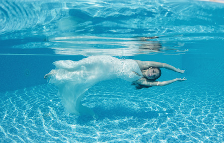 Beautiful woman girl dress underwater diving swim blue sunny day poolの写真素材