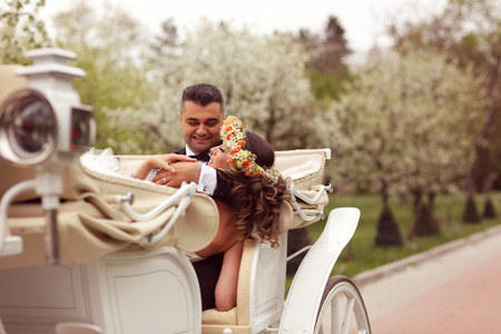 Bride and groom sitting in a white carriageの写真素材
