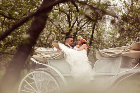 Bride and groom sitting in a white carriageの写真素材