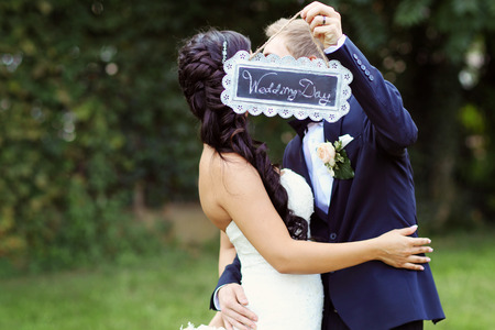 Beautiful bride and groom holding "Wedding day" signの写真素材